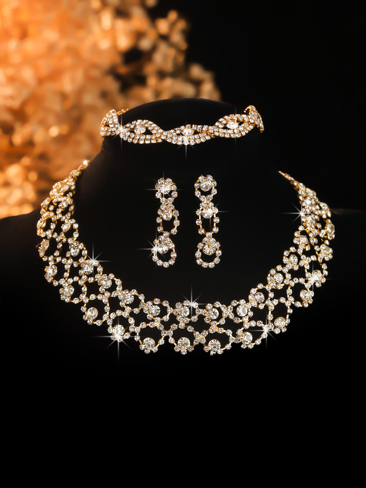 Gold-tone stone-set collar necklace and earrings on a black display bust
