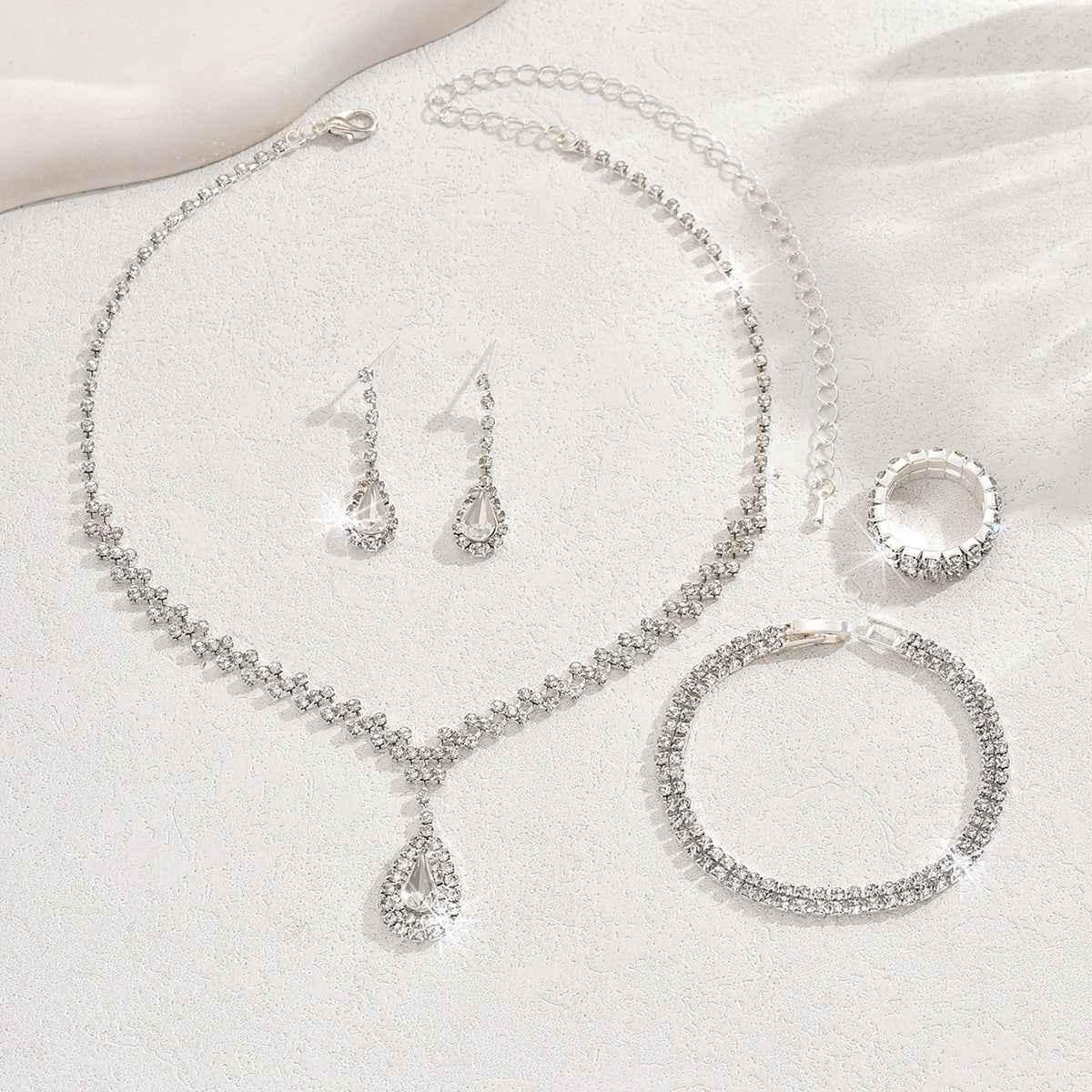 Teardrop rhinestone necklace, earrings and ring laid flat