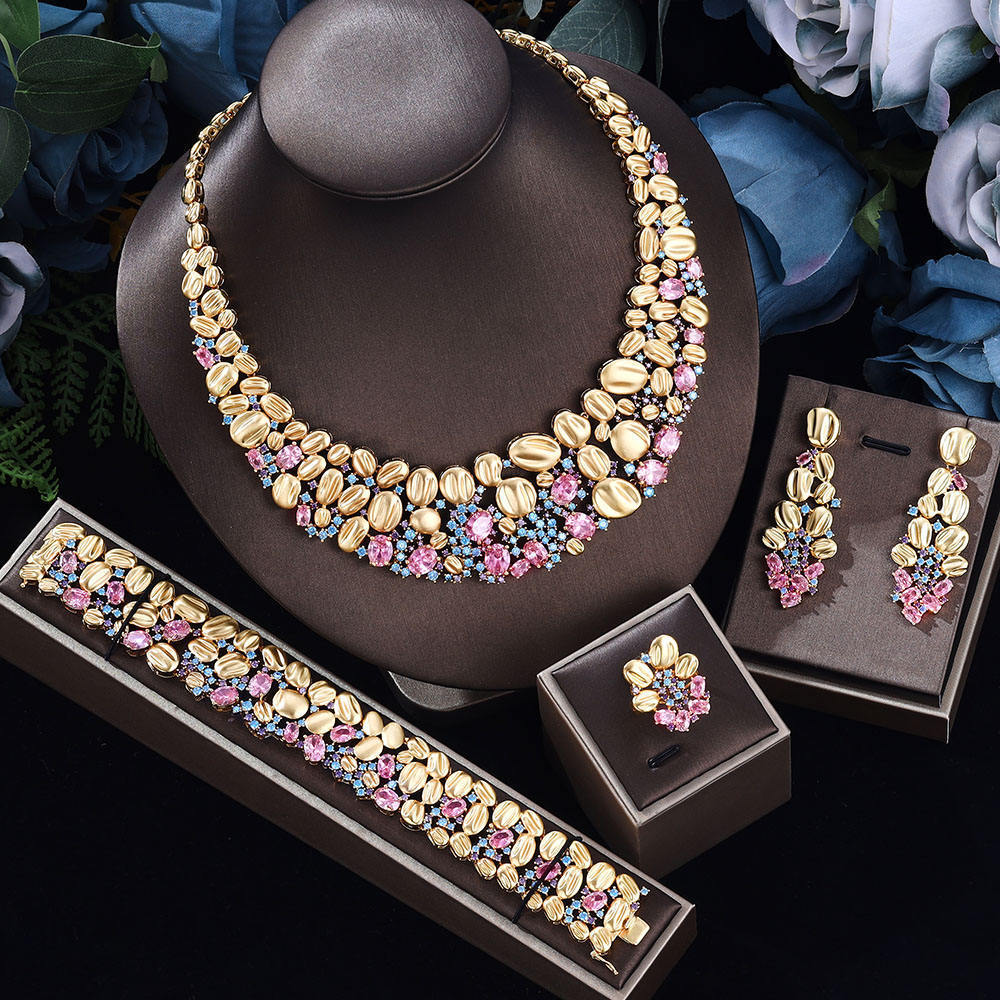 Oversized gold-tone necklace, earrings, bracelet and ring with pastel pink stones on a display bust