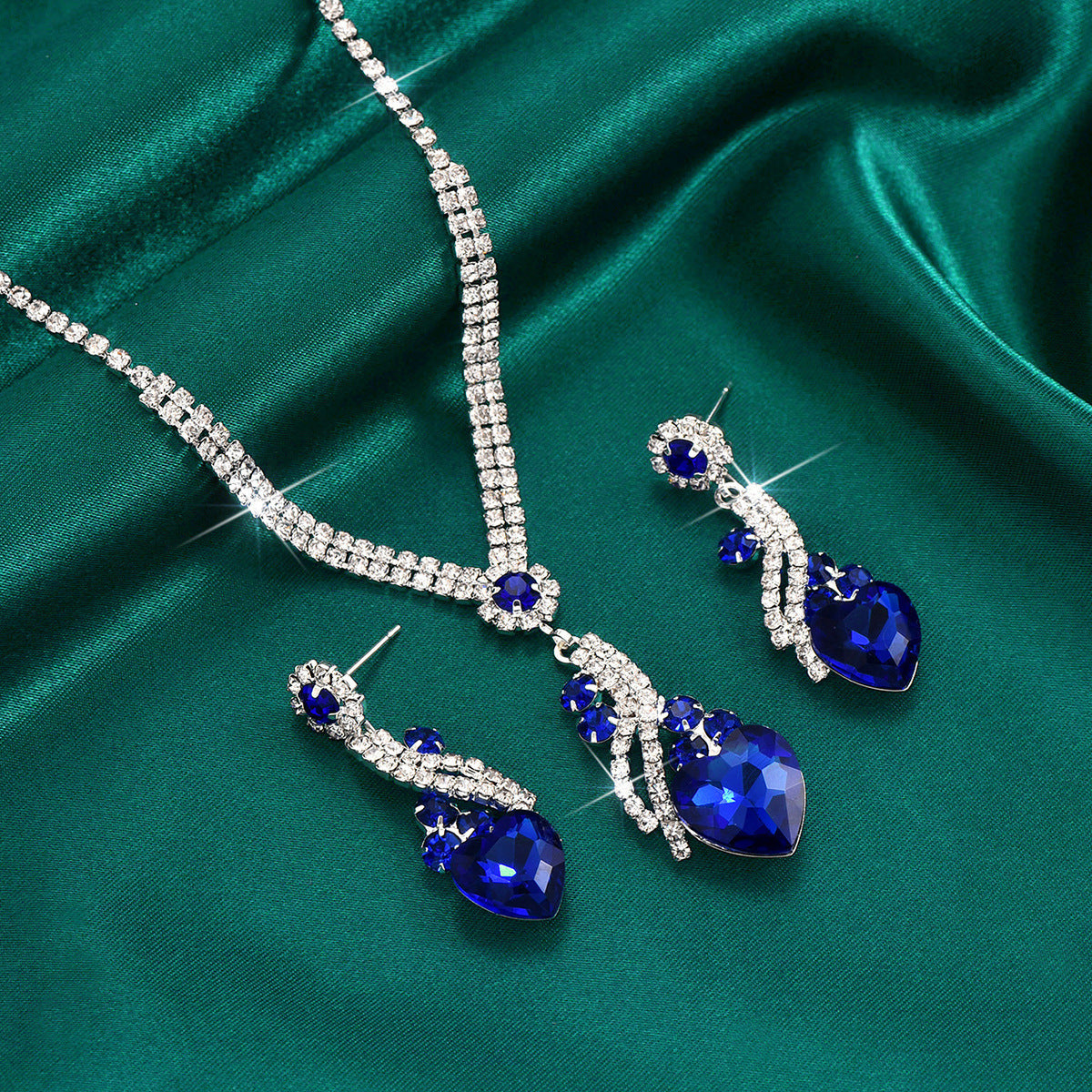 Royal blue crystal heart necklace and earrings on green satin