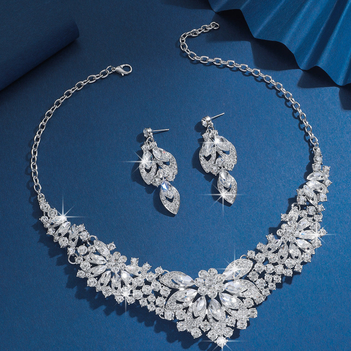 Clear rhinestone bridal necklace and matching earrings on a blue background