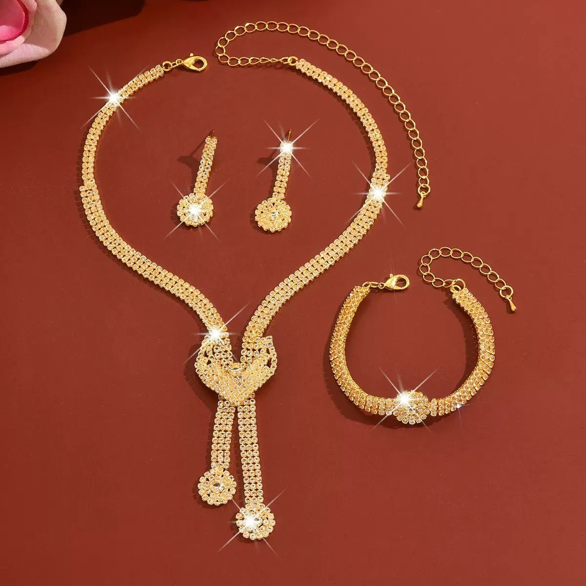 Gold-tone crystal necklace, earrings and bracelet on a red background