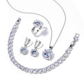 Clear round stone necklace, earrings, ring and tennis bracelet laid flat